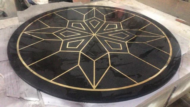 Круглое панно из тёмного гранита с геометрическим рисунком из латунных вставок